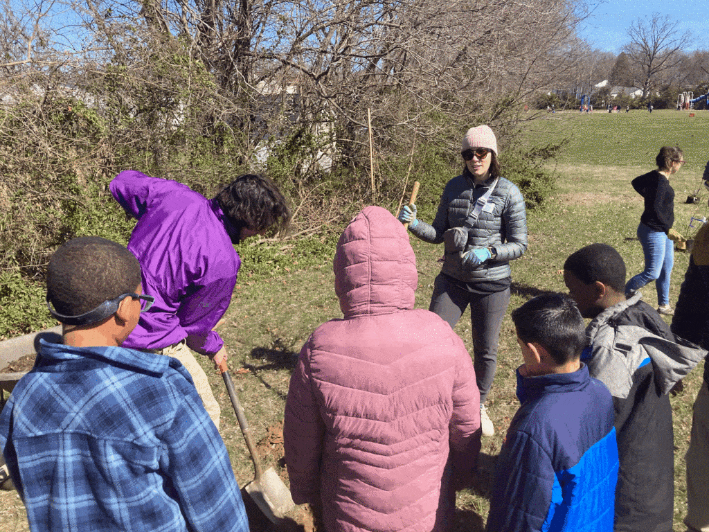 A teacher explains tree planting methods to the students.