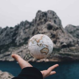 hand and globe in front of mountain