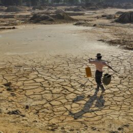 Man carrying water on cracked earth