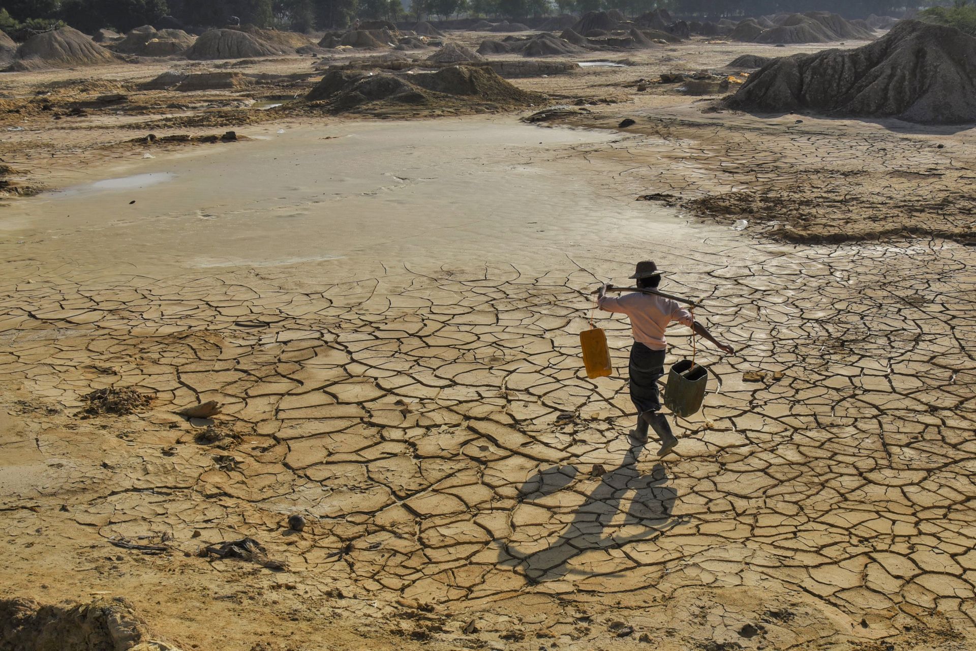 Man carrying water on cracked earth