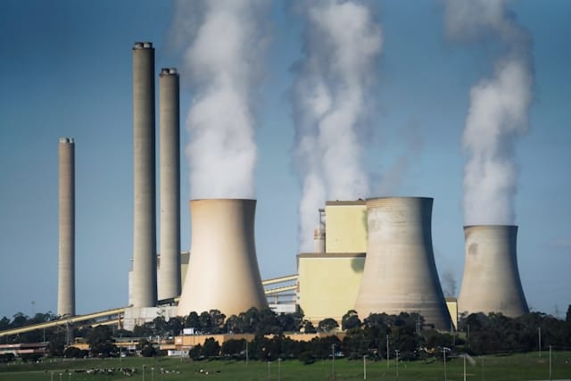 smoke billows from the cooling towers of a power plant