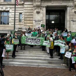 People stand on steps of DC City Hall holding banner of Green Budget Day of Action. Councilmember Charles Allen [center], joined by local and national environmental leaders, addresses the media during the DC Green Budget Day of Action.