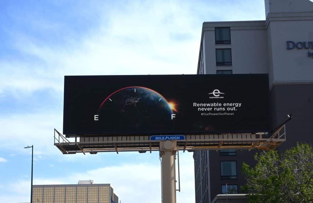 Billboard promoting renewable energy with a gas gauge overlaying the earth as seen from space, with the text "Renewable energy never runs out." and the EarthDay.ORG logo. #OurPowerOurPlanet