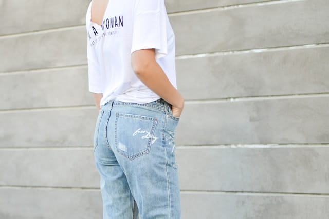woman in white shirt and blue denim bottoms facing the wal