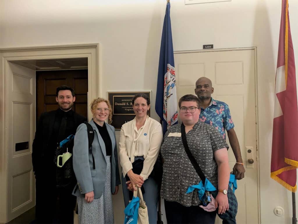 Five team members standing outside the office of Rep. Donald Beyer with flags