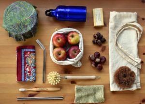 Zero-waste objects like reusable water bottle, canvas bags, and wooden toothbrush